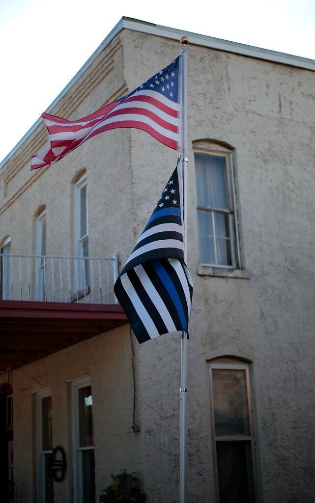 An American flag and a thin blue line flag wave in the late afternoon breeze at the main square in Osceola, Mo.